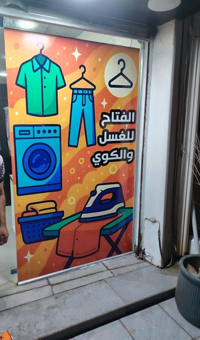 واجهة محل غسيل ملابس مغطاة بطباعة برتقالية مع اسم المحل