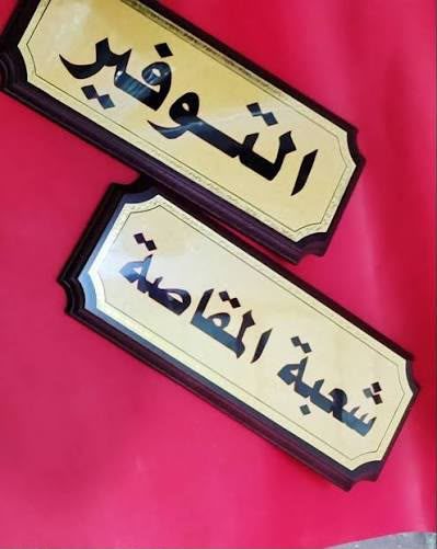 لافتتان مستطيلتان بلون ذهبي وإطار بني داكن مكتوب عليهما أسماء شعب إدارية