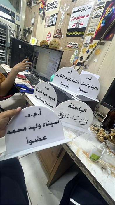 لافتات مكتبية بيضاء عليها أسماء أعضاء لجنة المناقشة داخل المطبعة